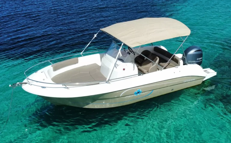 Pacific Craft 625 Open with a sun canopy and outboard engine anchored in turquoise water